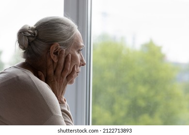 Upset lonely senior lady looking out of window with despair, frustration, going through depression, apathy, mental disorder, thinking over health problems, worried about memory loss, dementia