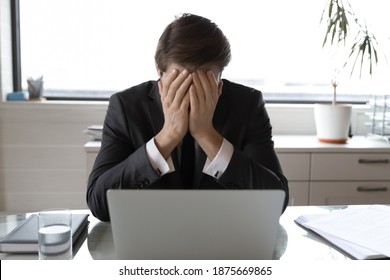 Upset Male Boss Or CEO Sit At Desk In Office Feel Distressed Frustrated With Bad Online News Message On Computer. Unhappy Businessman Work On Laptop Depressed With Business Failure Or Project Loss.