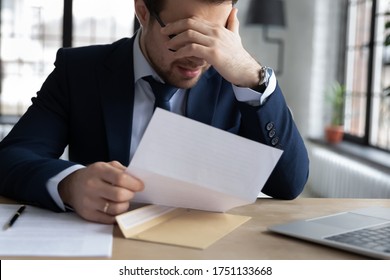 Upset male employer or boss sit at desk feel distressed disappointed reading post paper correspondence, unhappy employee frustrated by postal paperwork, get dismissal notice, fired, failure concept