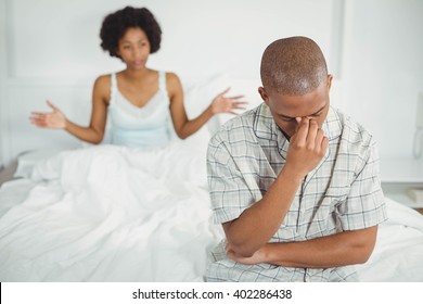 Upset man sitting on bed after arguing with his girlfriend