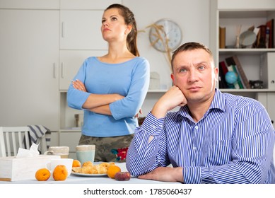 Upset Man Sitting At Table After Quarrel With Wife At The Home Table