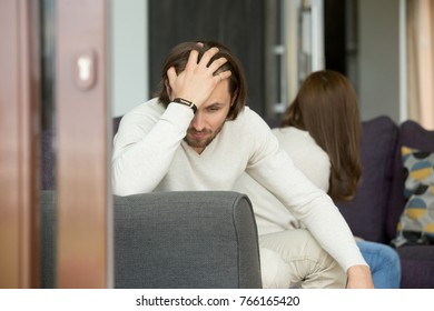 Upset Man Thinking Of Unresolved Problems Fed Up With Misunderstandings In Bad Relationships Sitting His Back To Frustrated Woman On Sofa At Home Holding Head In Hand, Unhappy Couple After Quarrel