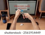 Upset man using online banking service and cutting his credit card with scissors. Account freeze alert on computer monitor, male client concerned about payment card freeze