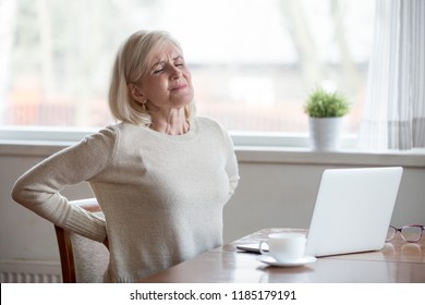 Upset mature middle aged woman feels back pain massaging aching muscles, sad senior older lady suffers from low-back lumbar pain sitting in incorrect sedentary posture, backache radiculitis concept