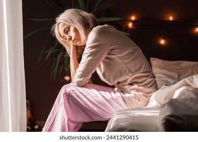 Upset middle-aged woman sit on bed in bedroom lost in thoughts thinking pondering of problem solution, depressed unhappy mature female look in distance suffer from depression, having personal problems - Powered by Shutterstock