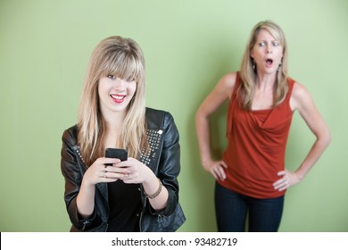 Upset Mom With Happy Teen On Mobile Phone