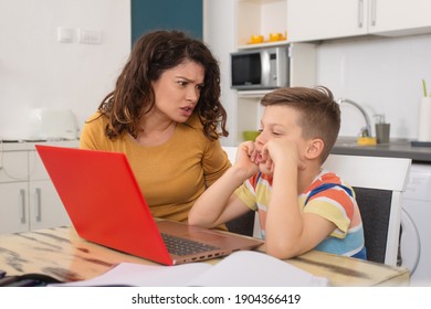 Upset mother looking in face of her son being silly while doing online class