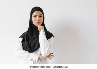 An Upset Muslim Woman In Hijab Thinking About Something And Wrinkling Her Forehead While Standing In The White Studio