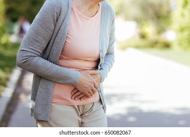 Upset Old Woman Having Sudden Pain In The Stomach Outdoors