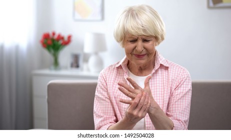 Upset old woman suddenly feeling sharp pain in wrist, arthritis health problem - Powered by Shutterstock