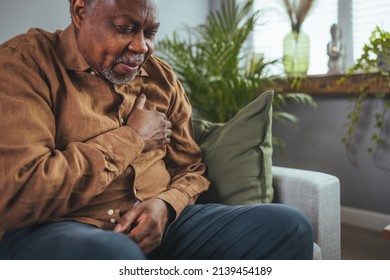 Upset Older Man Touching Chest, Talking On Phone, Unhappy Mature Male Having Heart Attack, Lonely Grandfather Suffering From Heartache Disease At Home, Feeling Pain, Sitting Alone. 