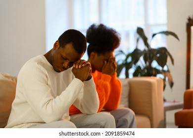 Upset Pensive African American Couple After Fight Sitting On Couch Separately Thinking Of Family Or Relationship Crisis, Conflict. Offended Man And Woman Avoid Looking At Each Other, Selective Focus