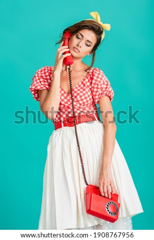 upset pin up woman talking on vintage phone isolated on turquoise