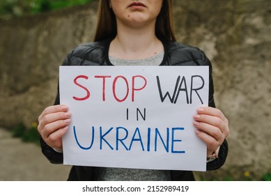 Upset Poor Girl Or Woman Protesting War Conflict Raises Banner With Inscription Message Text Stop War In Ukraine. Crisis, Peace, Stop Russian Aggression, Child Against War. No War.