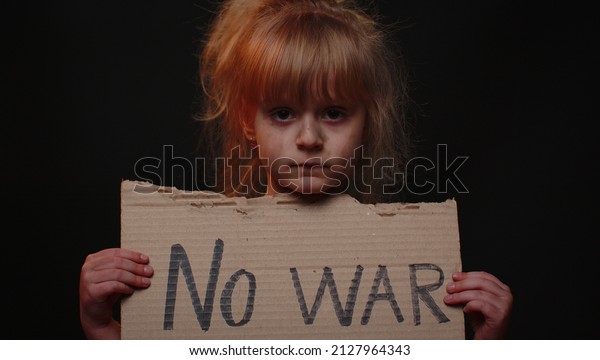 Upset poor toddler girl kid homeless with dirty face\
protesting war conflict raises banner with inscription massage text\
No War on black background. Crisis, peace, stop aggression, child\
against war