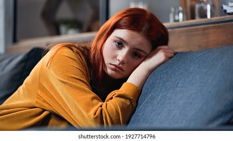 Upset Red Haired Teenager Looking At Camera On Couch 