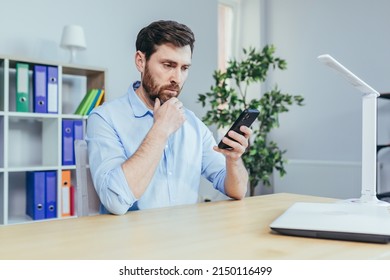 Upset And Sad Businessman Looking At Phone Screen, Man Working In Bright Office