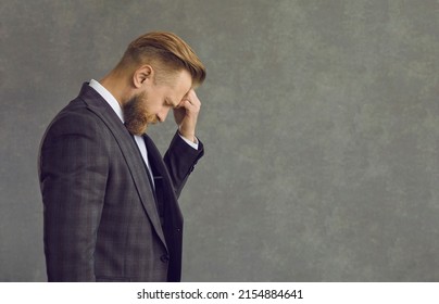 Upset Sad Depressed Businessman In Formal Suit Touching Head Suffering From Headache Side View. Studio Portrait Of People Emotion And Expression. Frustration And Unhealthy Anxiety Person Concept