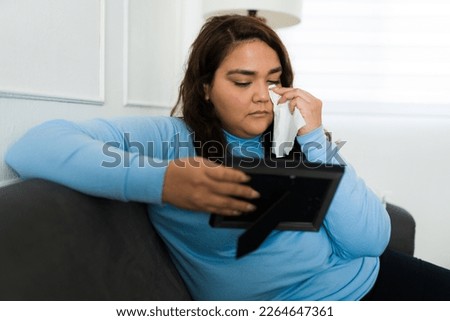 Upset sad overweight woman crying and using tissues while missing her ex partner after her breakup
