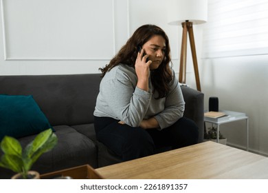 Upset sad young woman looking depressed while talking on the phone or calling someone asking for help because of her mental health problems - Shutterstock ID 2261891357