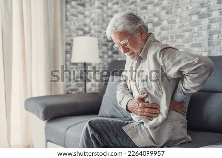 Upset senior elder man feel sudden back pain muscles ache tension injury sitting at home, sad old grandfather touching spine having lower lumbago backache osteoarthritis arthritis, backache concept