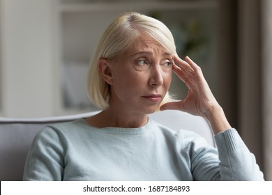 Upset Senior Woman Sit On Couch At Home Look In Distance Mourning, Sad Distressed Mature Female Lost In Thoughts, Miss Old Days, Thinking Or Pondering, Feeling Lonely, Elderly Solitude Concept