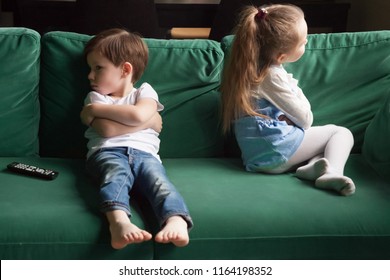 Upset siblings boy and girl sulking sitting with arms crossed on sofa not talking, kids brother sister ignoring each other after fight about tv channel choice, children conflicts and rivalry concept