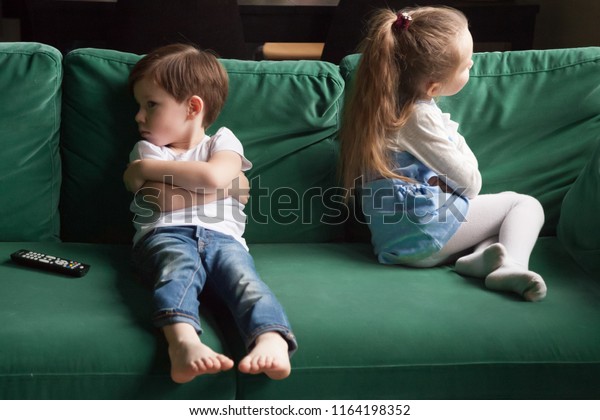 Upset siblings boy and girl sulking sitting with\
arms crossed on sofa not talking, kids brother sister ignoring each\
other after fight about tv channel choice, children conflicts and\
rivalry concept