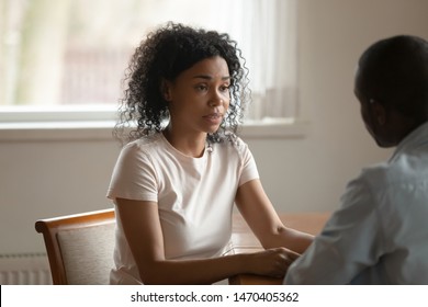 Upset stressed african american woman sharing health problems, disease, telling bad news to husband, feeling desperate. Sad black man discussing difficulties in family relationship with unhappy wife.