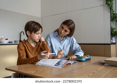 Upset stressed child boy feeling frustrated while doing homework with mom at home. Kid sitting at kitchen table with teacher tutor having difficulties in learning. Problems with homeschooling - Powered by Shutterstock