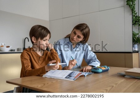 Upset stressed child boy feeling frustrated while doing homework with mom at home. Kid sitting at kitchen table with teacher tutor having difficulties in learning. Problems with homeschooling
