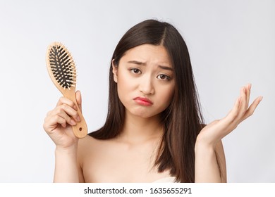 Upset Stressed Young Asian Woman Holding Damaged Dry Hair On Hands Over White Isolated Background.