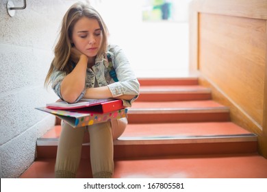 Upset Student Sitting On Stairs In College