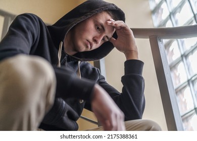 upset tense young man in a hood, sitting on the stairs and looking away, experiencing problems and misunderstanding. Teenage transition age. The concept of loneliness. Close-up - Shutterstock ID 2175388361