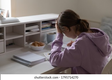 Upset tired teenage girl studying at home rear view, touching forehead, suffering from headache, lazy unmotivated teen schoolgirl student sitting at desk, difficult school assignment task, homework - Powered by Shutterstock
