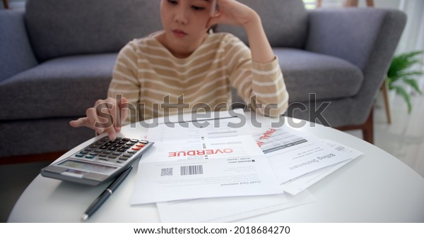Upset tired young asia sad lady people sit sofa\
couch at home think hard worry in tax expense saving issue past due\
loan late payment on covid impact life feel grief pensive struggle\
in money lost.