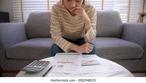 Upset Tired Young Asia Woman Sit On Sofa At Home Think Hard Worry In Tax Expense Saving Issue Past Due Loan Late Payment On Covid Impact Life.