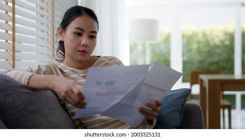 Upset Tired Young Asia Woman Sit On Sofa At Home Think Hard Worry In Tax Expense Saving Issue Past Due Loan Late Payment On Covid Impact Life.