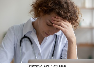 Upset Tired Young Caucasian Female Nurse Feel Frustrated Distressed With Overwork Late Hours In Hospital, Stressed Woman Doctor Or GP Suffer From Headache Or Migraine, Have Hard Working Day In Clinic