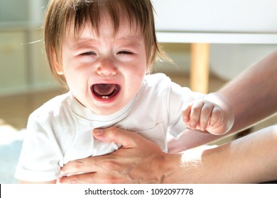 Upset Toddler Boy Crying While Being Held By His Father