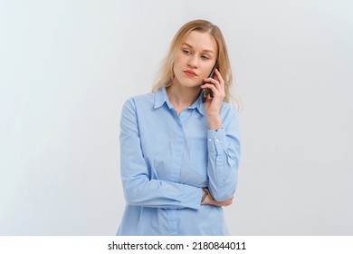 Upset And Unhappy Blonde Woman Talking On Mobile Phone, Conversation On Smartphone, Standing Over White Background In Casual Blue Shirt. Cellphone, Cellular Concept