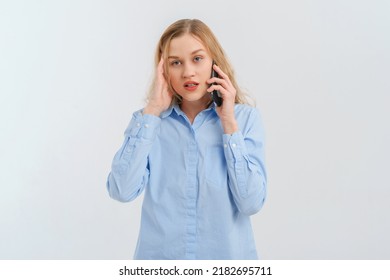 Upset And Unhappy Blonde Woman Talking On Mobile Phone, Conversation On Smartphone, Standing Over White Background In Casual Blue Shirt. Cellphone, Cellular Concept