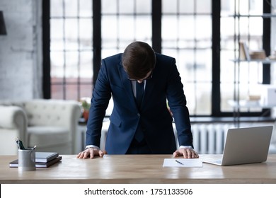 Upset unsuccessful Caucasian businessman stand at desk in office feel stressed after business startup failure, unhappy distressed male boss director stressed with company bankruptcy, money loss