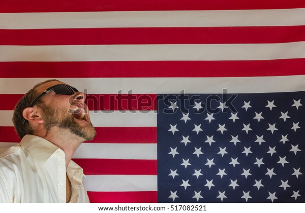 Upset of U.S. Presidential election. \
Man in front of upside down American flag. \
