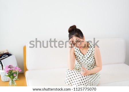 Upset Vietnamese woman on couch at home in the living room