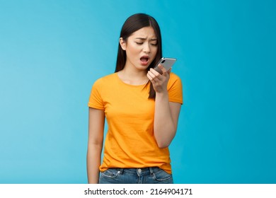 Upset whining displeased moody girlfriend complaining talk into smartphone hold phone near mouth upset, frowning bothered bad connection, record voice message, blue background