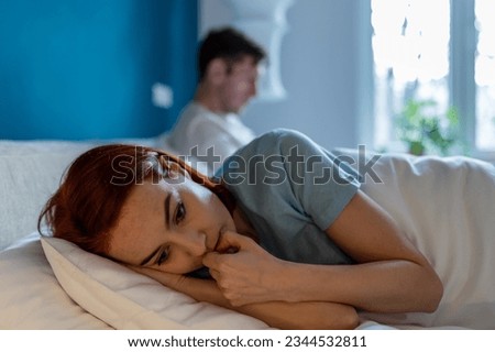 Upset wife lies with her back to husband. Frustration, unhappiness, pain, resentment and thoughtfulness on face of sad depressed woman lying in bed thinking. Man with disinterested look ignores woman. Сток-фото © 