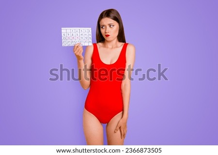 Upset woman holding calendar in hand and looking to the side with sad eyes isolated on vivid yellow background