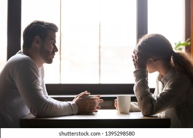 Upset woman and man talking in cafe about problem in relationships, frustrated girlfriend hiding face in hands, couple sitting at table in coffeehouse together, drinking coffee, bad first date