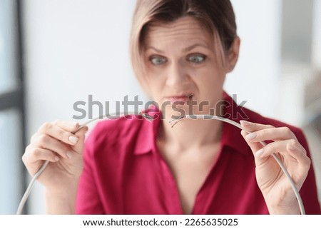 Upset woman in the office with a broken network cable in her hands, close-up. The concept of no internet